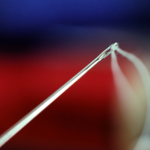 a close up of a needle with a red, white and blue background