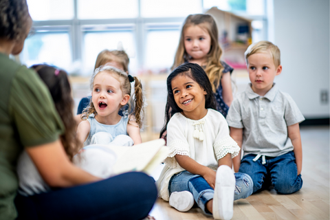 A group of young children smiling at an adult