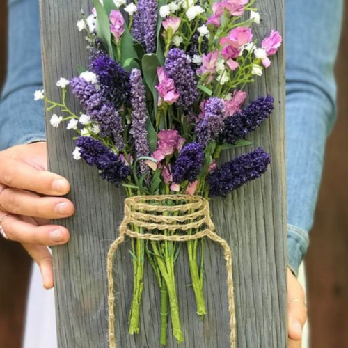 a person holding a bouquet of flowers in a mason jar