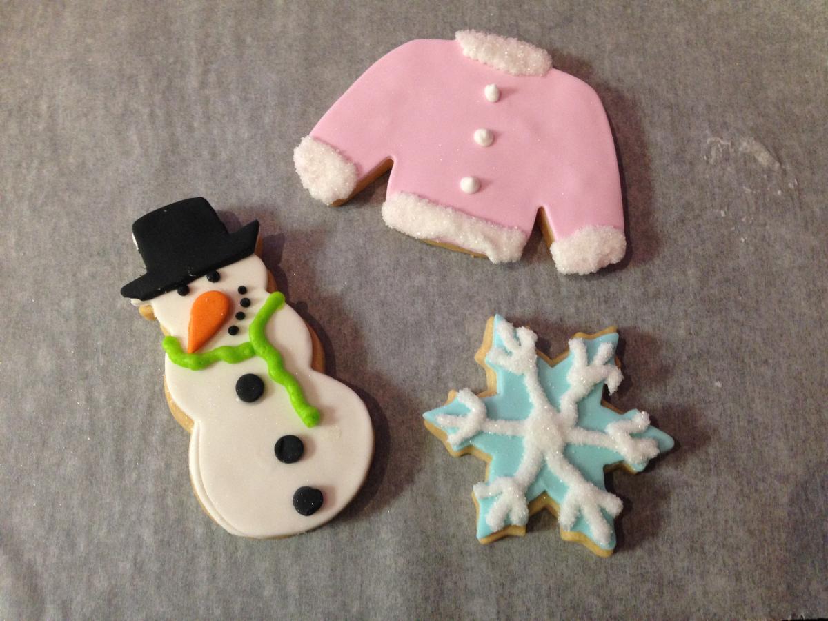 Grey background with winter cookies: sweater, snowman, and snowflake.
